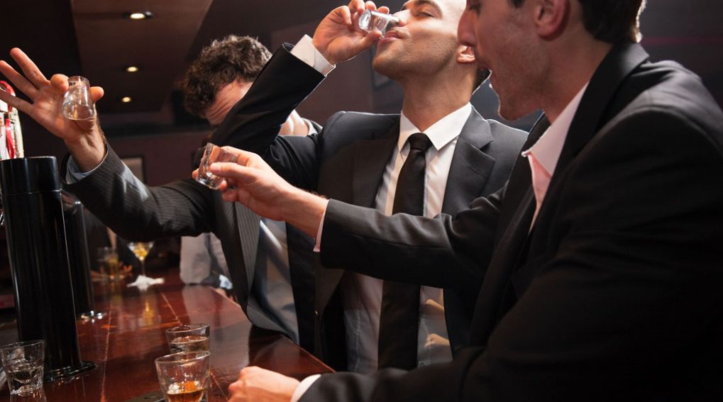 Businessmen drinking shots in bar